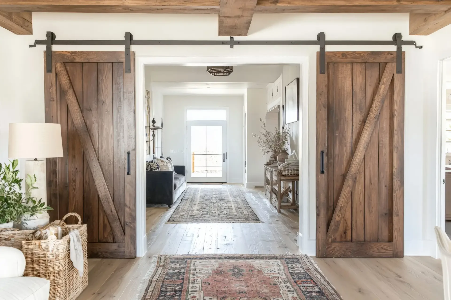 Custom rustic wood sliding barn doors with black hardware in open living space with hardwood flooring, installed by Dorsey Builders in Dothan, AL.