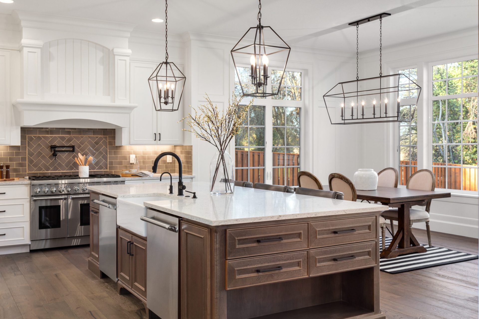 Modern kitchen with large island, stainless steel appliances, pendant lighting, and dining area, designed by Dorsey Builders in Dothan, AL.