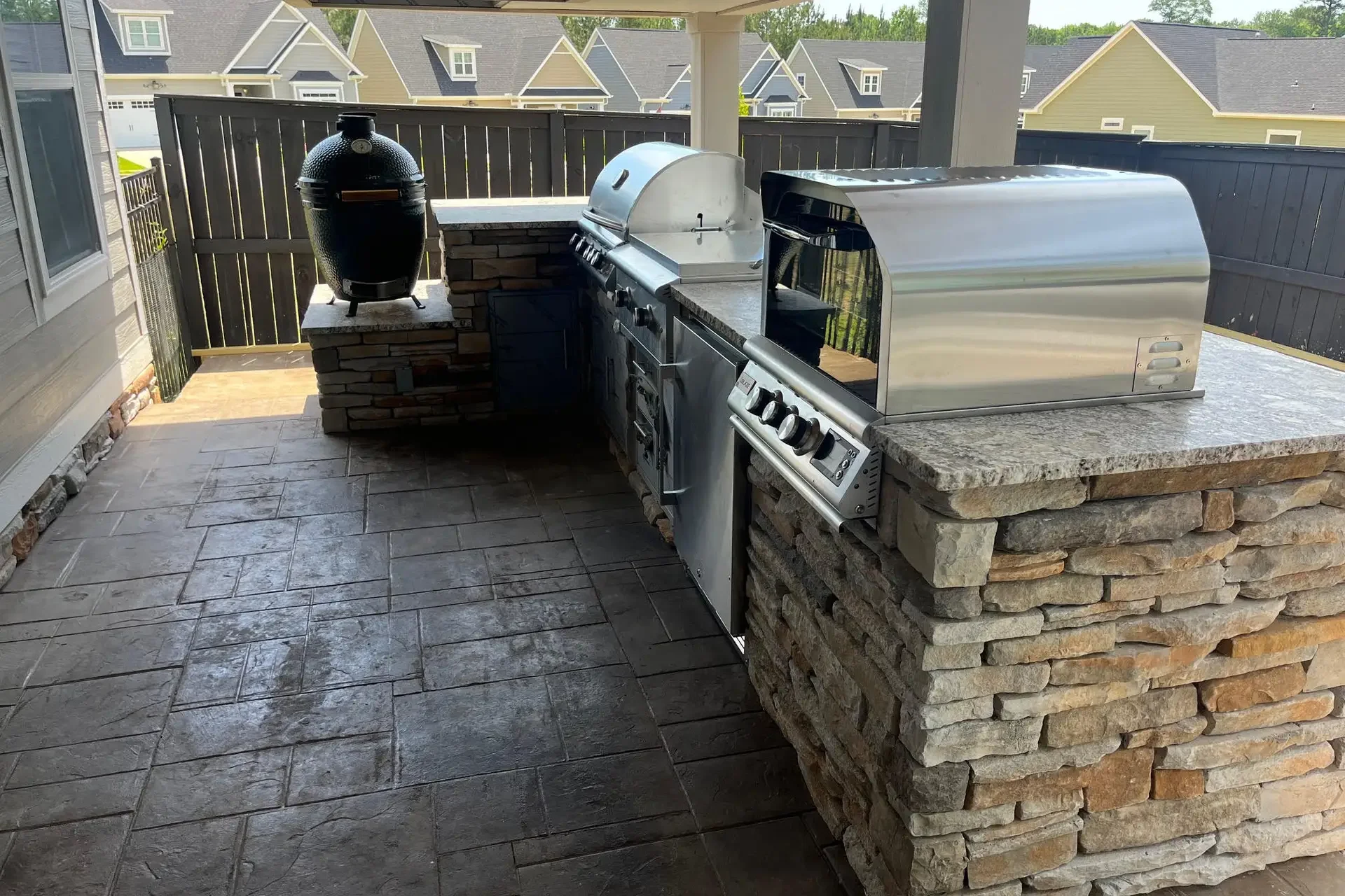 Custom outdoor kitchen with stacked stone, grill, smoker, and pizza oven for homes in Dothan, Alabama