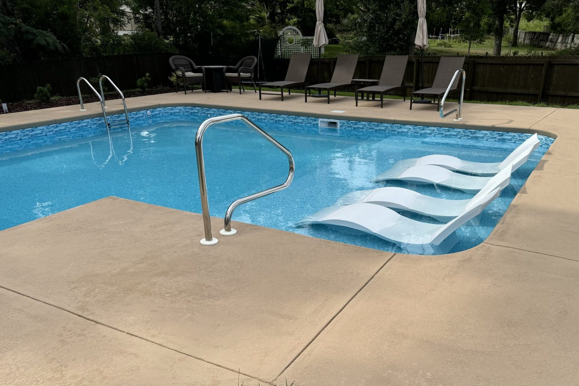Inground swimming pool with built-in tanning ledge and modern poolside loungers, crafted by Dorsey Builders, custom home builder in Dothan, AL.