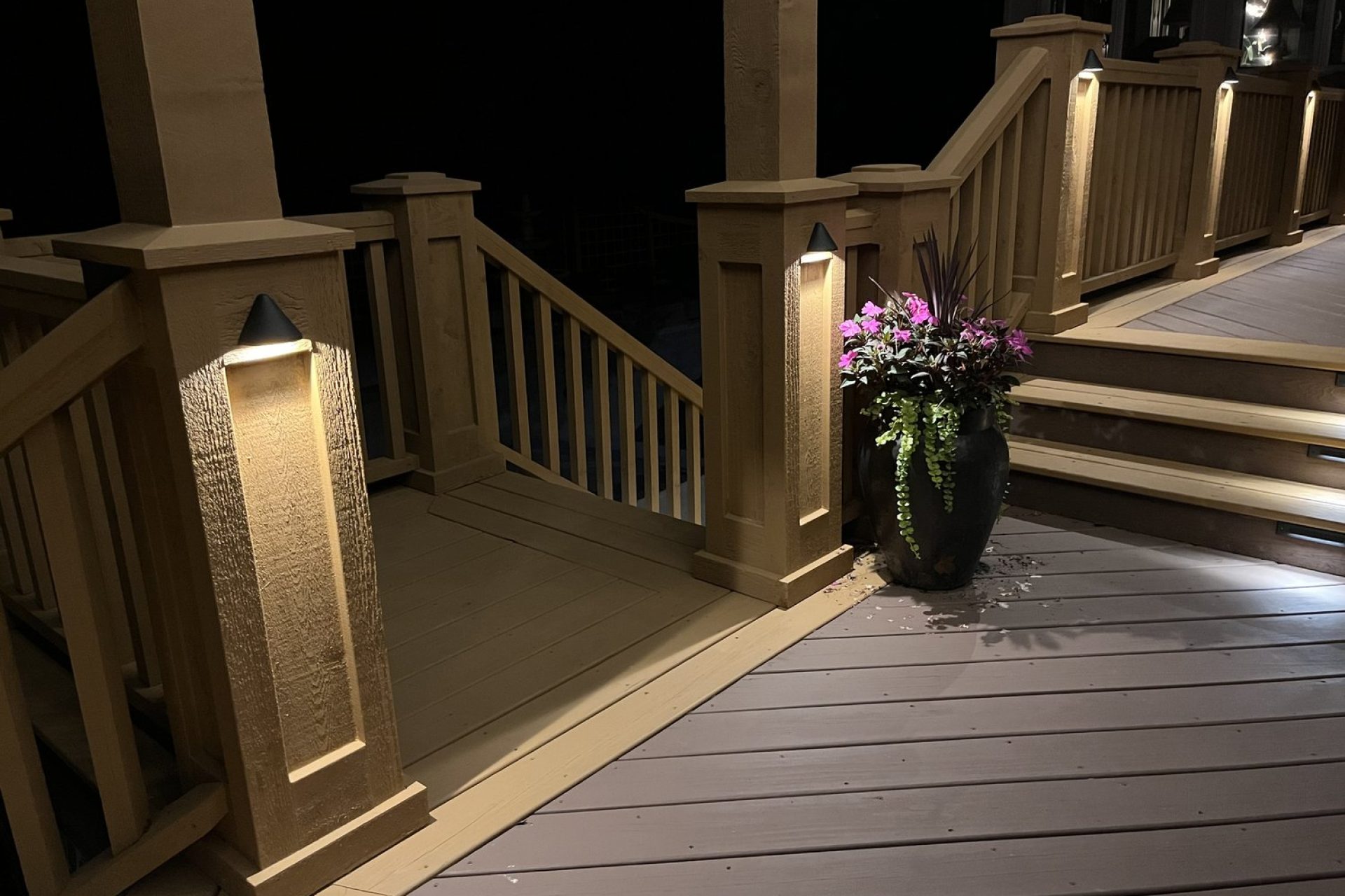 Custom-built wood deck with decorative railing, integrated step lighting, and potted flowers, designed for outdoor living by Dorsey Builders in Dothan, Alabama.