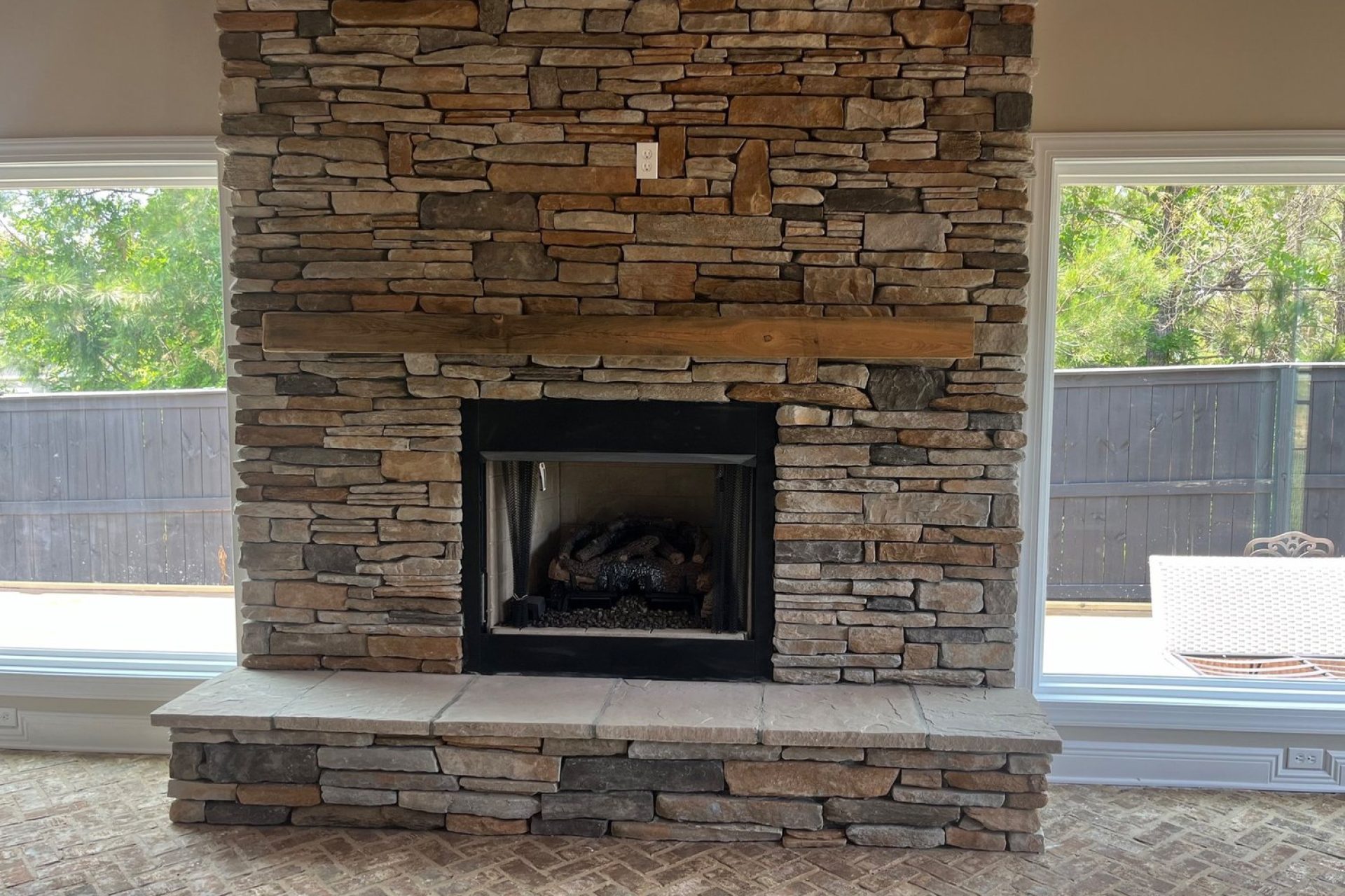 Rustic stacked stone fireplace with wood mantel in custom-built home interior, crafted by Dorsey Builders, residential construction experts in Dothan, AL.