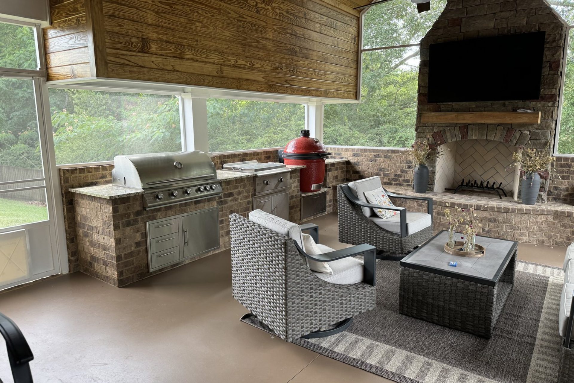 Screened-in outdoor kitchen and fireplace with built-in grill, stone fireplace, and modern seating area, crafted by Dorsey Builders, custom home builder in Dothan, Alabama.
